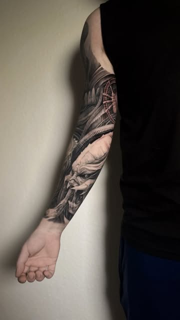 Detailed black and grey tattoo flowing along a forearm